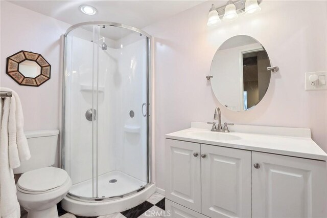 bathroom featuring vanity, a shower with door, and toilet