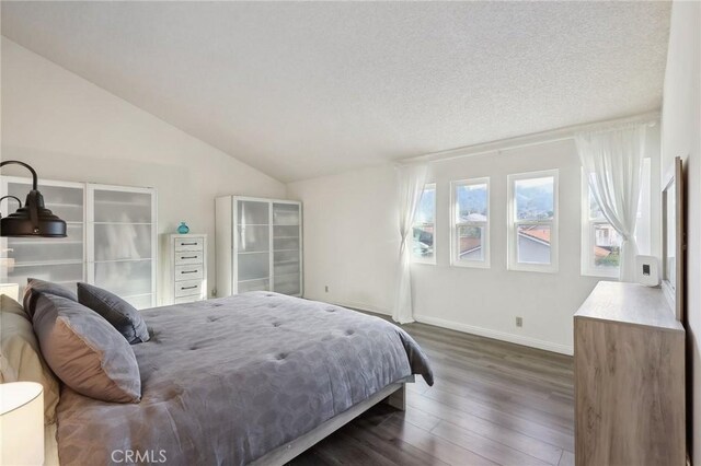 bedroom with lofted ceiling, dark wood-type flooring, and a textured ceiling