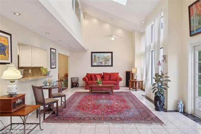 living room featuring a high ceiling, light tile patterned floors, and ceiling fan