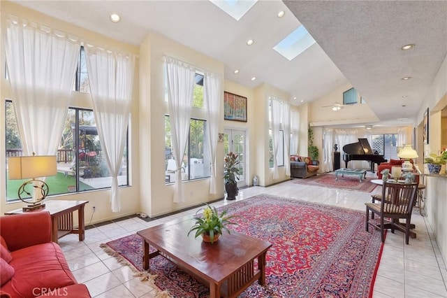 living area featuring a skylight, light tile patterned floors, a wealth of natural light, and high vaulted ceiling