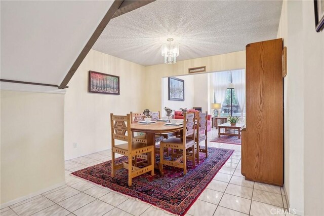 tiled dining space featuring a textured ceiling and a notable chandelier