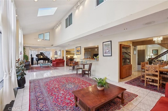 interior space featuring light tile patterned floors, stairway, a skylight, and high vaulted ceiling