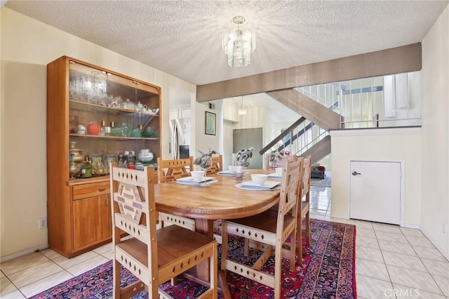 tiled dining space featuring a textured ceiling and a notable chandelier