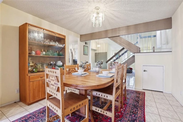 dining space featuring light tile patterned flooring, a chandelier, a textured ceiling, and stairs