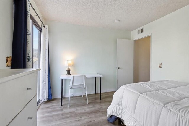 bedroom featuring a textured ceiling and light hardwood / wood-style flooring