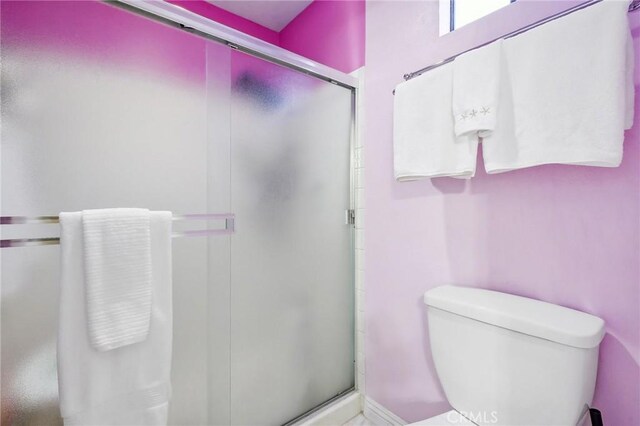 bathroom with toilet and a shower with shower door