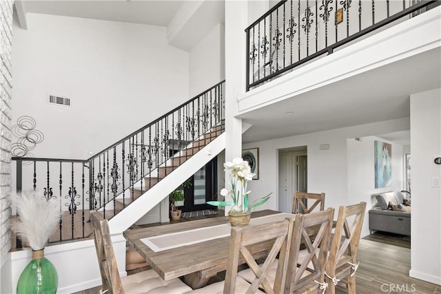 dining space with a high ceiling, wood finished floors, and visible vents