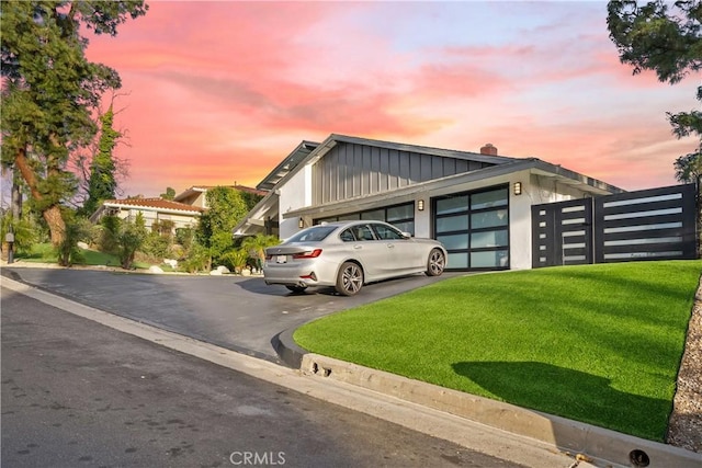 exterior space featuring driveway, board and batten siding, an attached garage, and a front yard