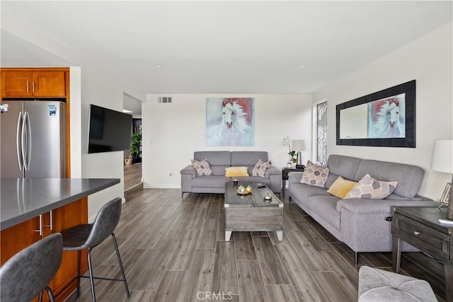 living room with wood tiled floor, visible vents, and baseboards