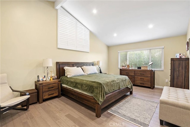 bedroom with vaulted ceiling, baseboards, and light wood-style floors