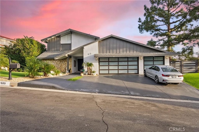 view of front of property with a garage, stone siding, driveway, and fence