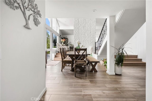 dining room with stairs, a high ceiling, wood finished floors, and baseboards