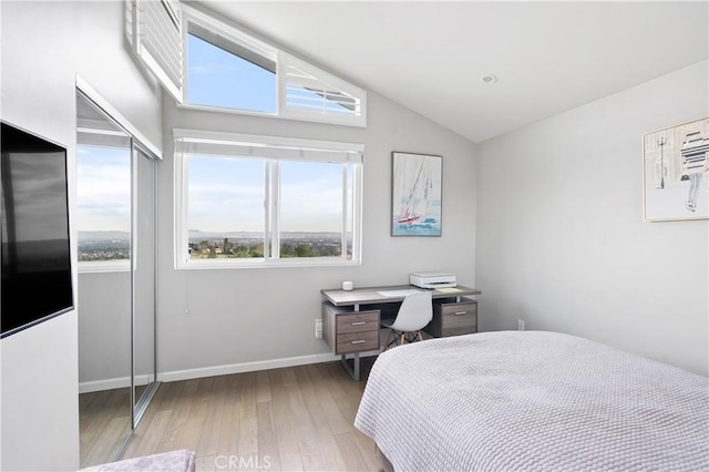 bedroom with lofted ceiling, baseboards, and wood finished floors