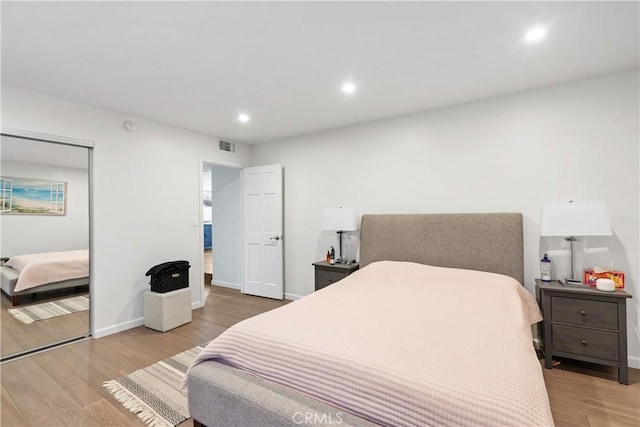 bedroom featuring baseboards, visible vents, wood finished floors, a closet, and recessed lighting