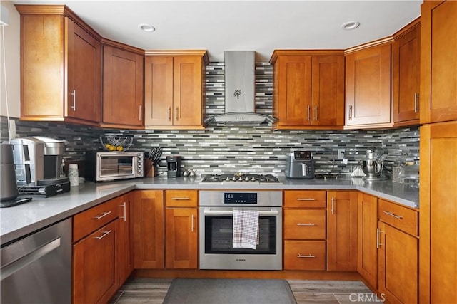 kitchen with stainless steel appliances, a toaster, backsplash, and wall chimney exhaust hood