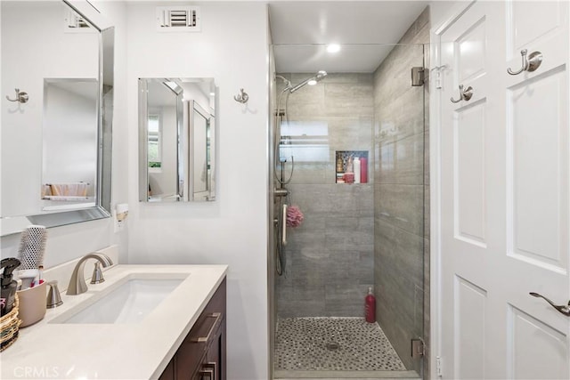 full bathroom with a stall shower, visible vents, and vanity