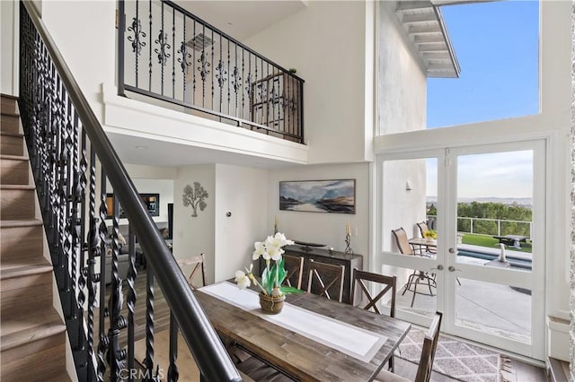 interior space featuring wood finished floors, french doors, a towering ceiling, and stairs