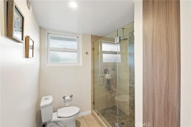 full bathroom with a stall shower, baseboards, tile patterned flooring, and toilet