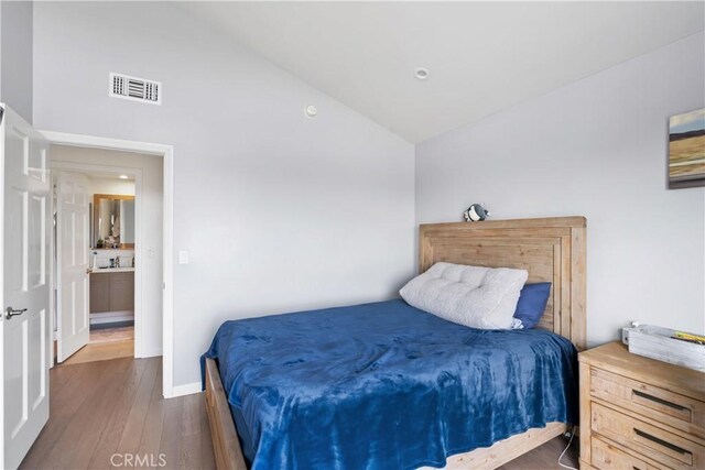 bedroom featuring lofted ceiling, baseboards, visible vents, and wood finished floors