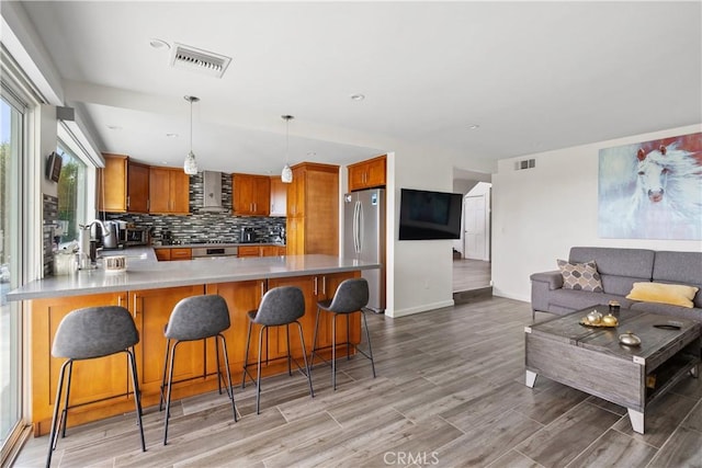 kitchen with brown cabinets, freestanding refrigerator, visible vents, and a peninsula