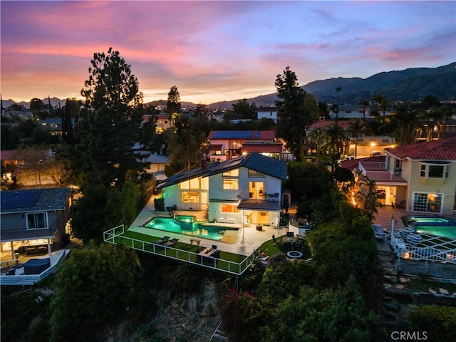 back of house with a fenced in pool, a patio area, a mountain view, and a balcony