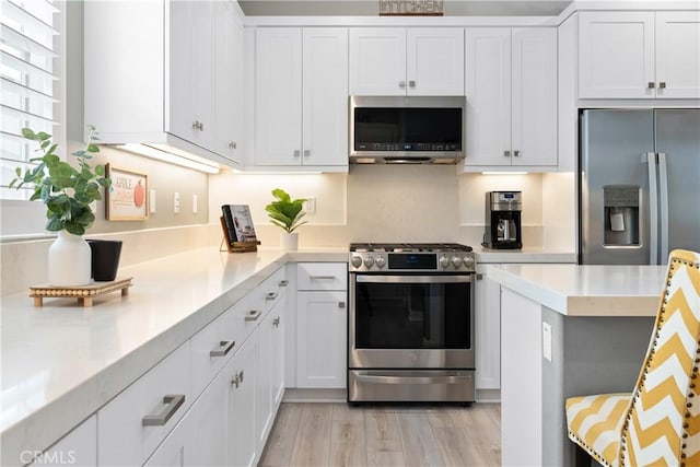 kitchen with appliances with stainless steel finishes, light hardwood / wood-style flooring, and white cabinets