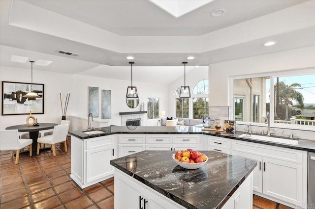 kitchen with white cabinetry, decorative light fixtures, a center island, and sink