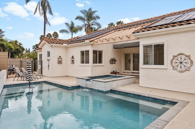 rear view of house featuring a pool with hot tub, a patio area, and solar panels