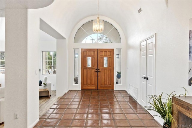 tiled foyer with lofted ceiling and an inviting chandelier