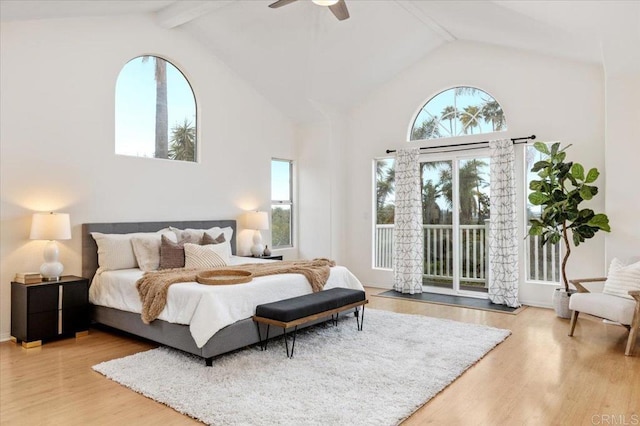 bedroom with beamed ceiling, hardwood / wood-style flooring, access to exterior, and multiple windows