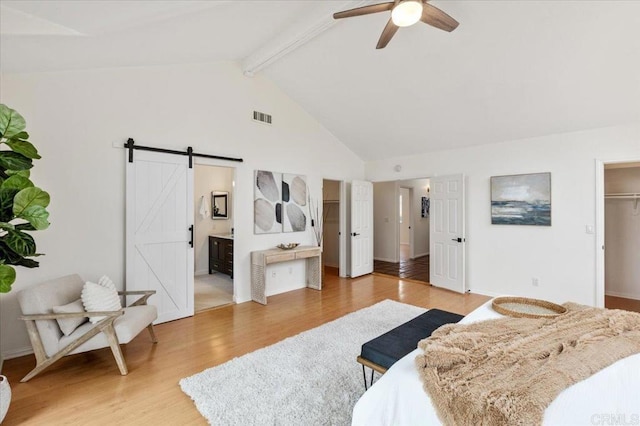 bedroom with hardwood / wood-style floors, high vaulted ceiling, a spacious closet, a barn door, and beam ceiling