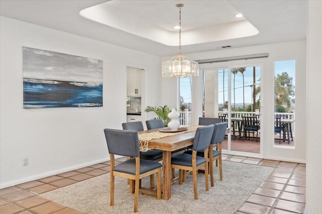 tiled dining room with a notable chandelier and a tray ceiling