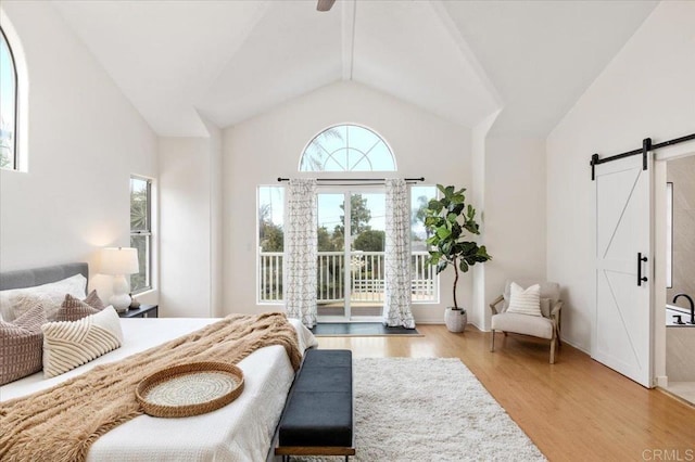 bedroom featuring lofted ceiling, light hardwood / wood-style flooring, access to outside, ceiling fan, and a barn door