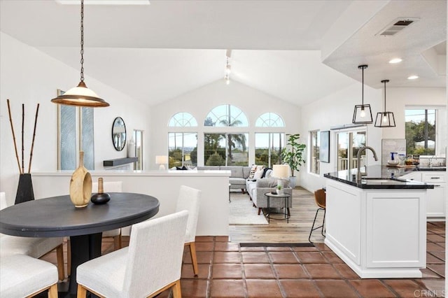 kitchen with lofted ceiling, sink, hanging light fixtures, and white cabinets