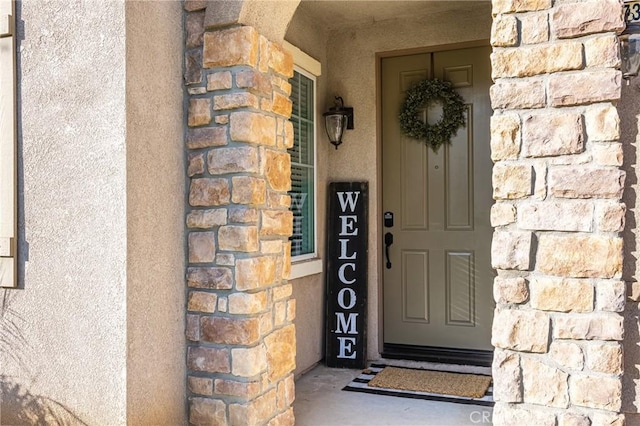 property entrance featuring stone siding and stucco siding