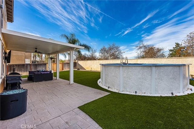 view of yard featuring a fenced in pool, outdoor lounge area, a patio, and ceiling fan