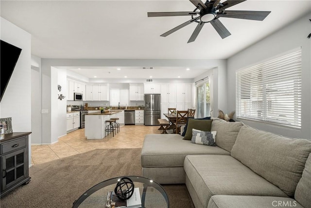 living room featuring ceiling fan, light tile patterned floors, light colored carpet, and recessed lighting