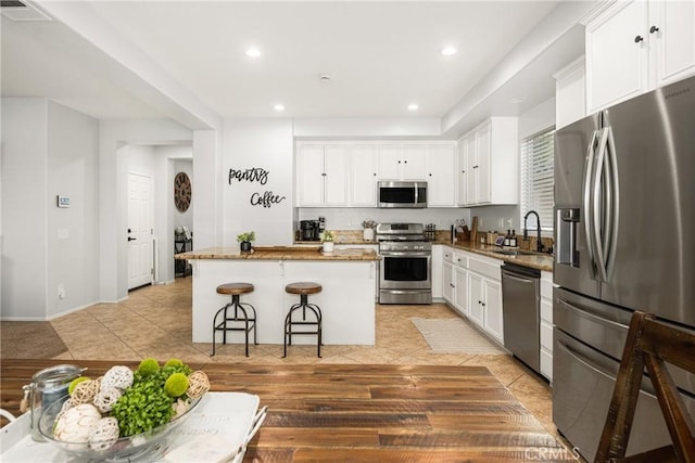 kitchen featuring sink, stainless steel appliances, a center island, and white cabinets