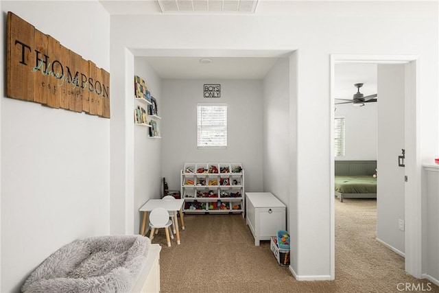 recreation room with light carpet, ceiling fan, visible vents, and baseboards