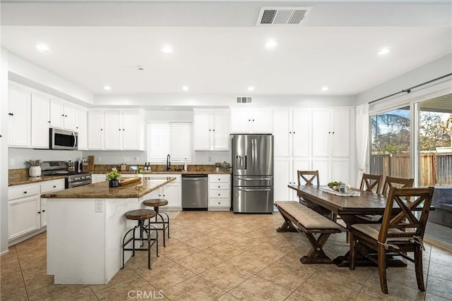 kitchen featuring stainless steel appliances, a kitchen island, and white cabinetry