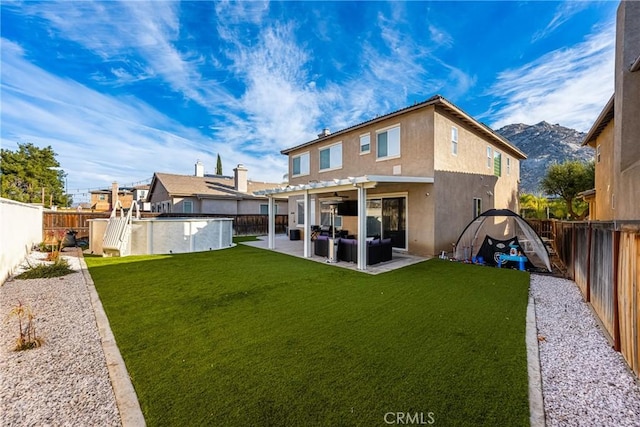 rear view of property featuring a pergola, a patio area, a lawn, and a mountain view