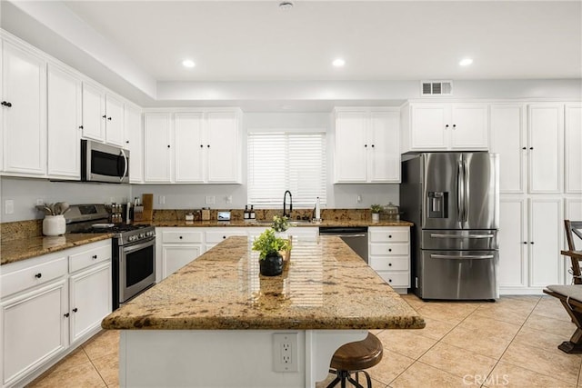 kitchen with visible vents, appliances with stainless steel finishes, stone countertops, and a center island