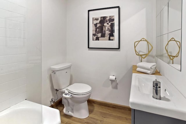 bathroom featuring vanity, a tub to relax in, wood-type flooring, and toilet