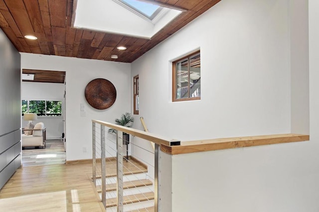 hallway featuring wood ceiling, a skylight, and light wood-type flooring