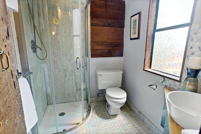 bathroom featuring tile patterned flooring, toilet, sink, and walk in shower