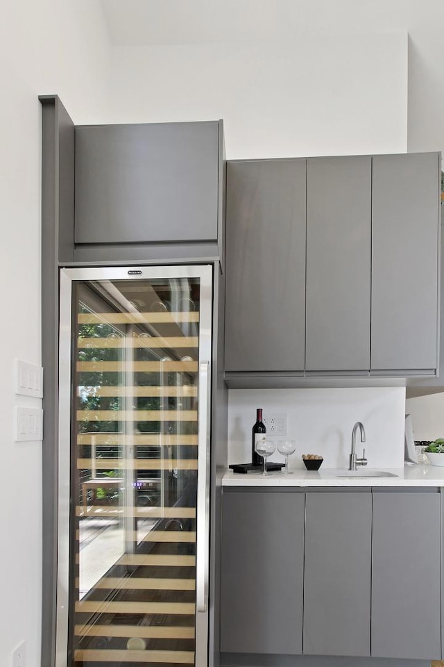 bar featuring wine cooler, sink, and gray cabinets