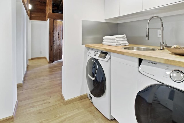 washroom with separate washer and dryer, sink, and light wood-type flooring