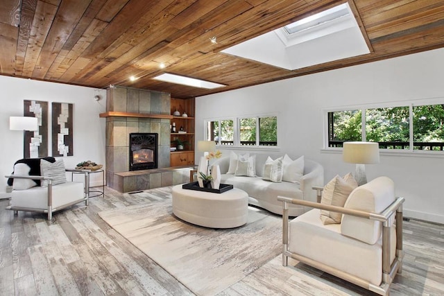 living room featuring a skylight, a tile fireplace, wooden ceiling, and light hardwood / wood-style flooring