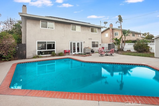 back of property with a fenced in pool, a patio, and french doors