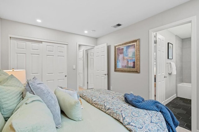 bedroom with ensuite bath, a closet, and dark tile patterned floors